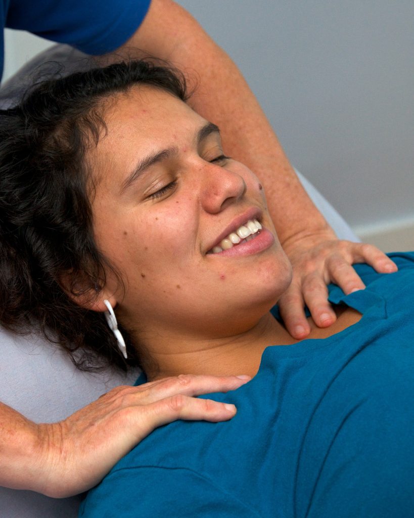 A woman getting massaged wearing blue and smiling